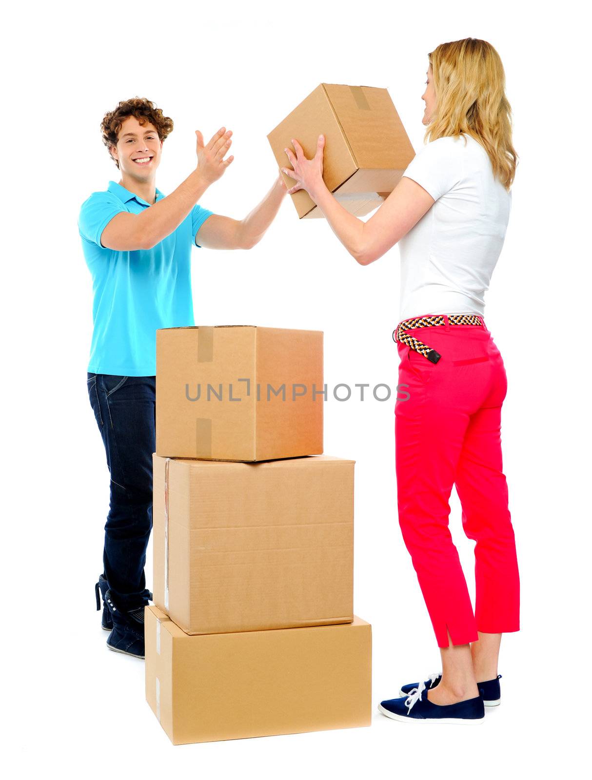 Woman passing cardboard cartons to man  while he stacks them