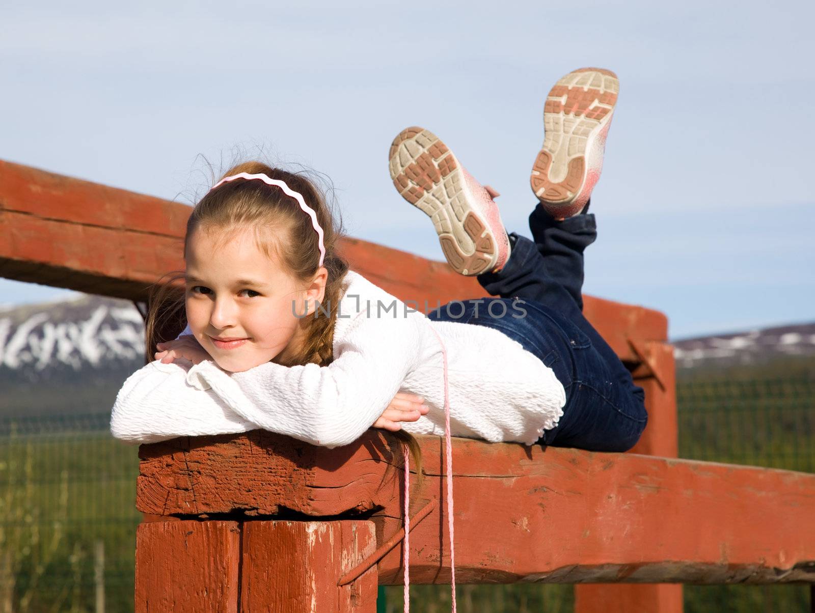 A girl lies on the balance beam in an open sports field