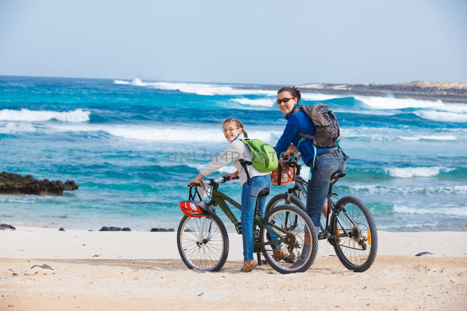 Girl with her mother having a weekend excursion on their bikes on a summer day in beautiful sea landscape