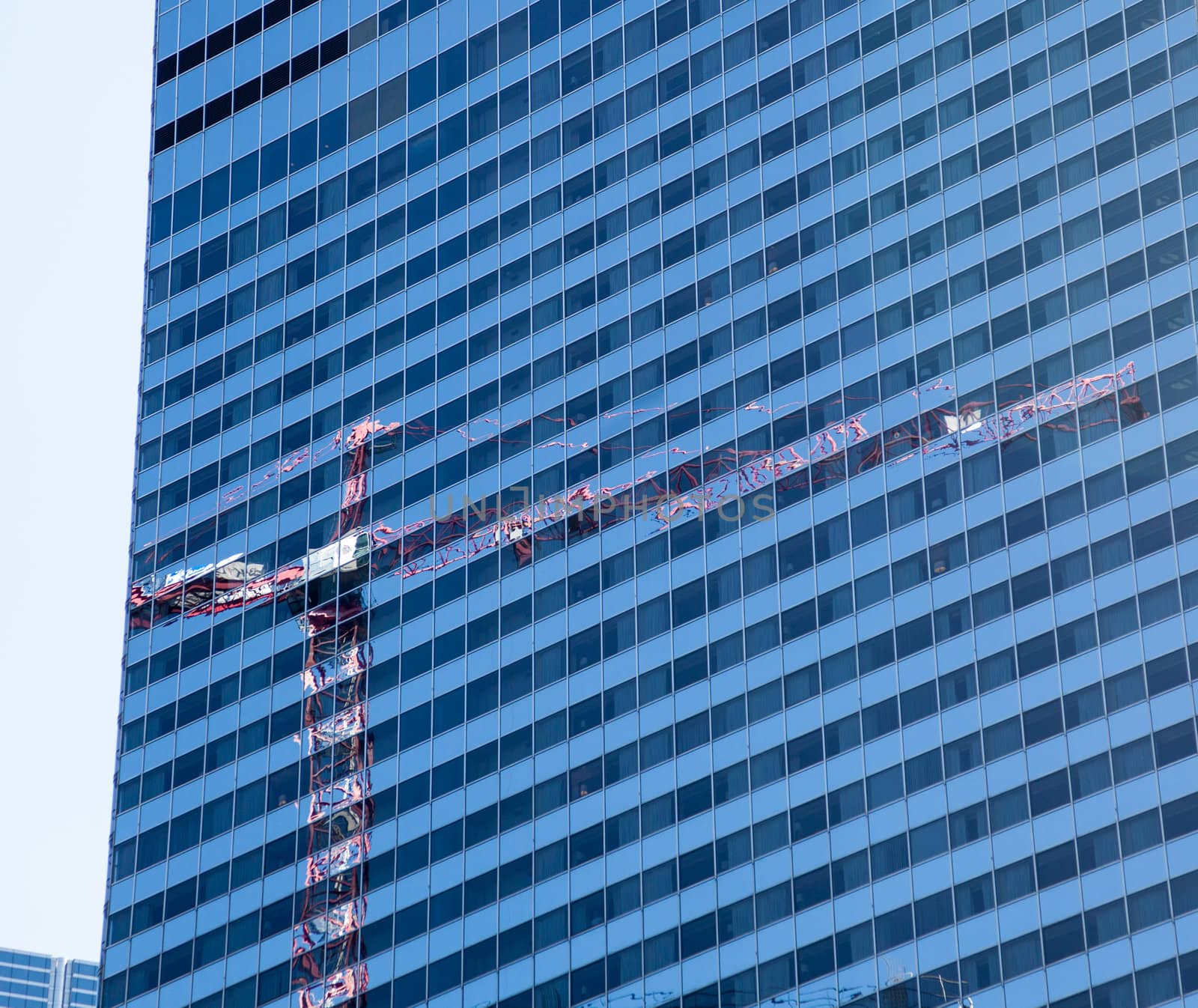 Reflection of construction crane in Chicago in the blue windows of a skyscraper opposite