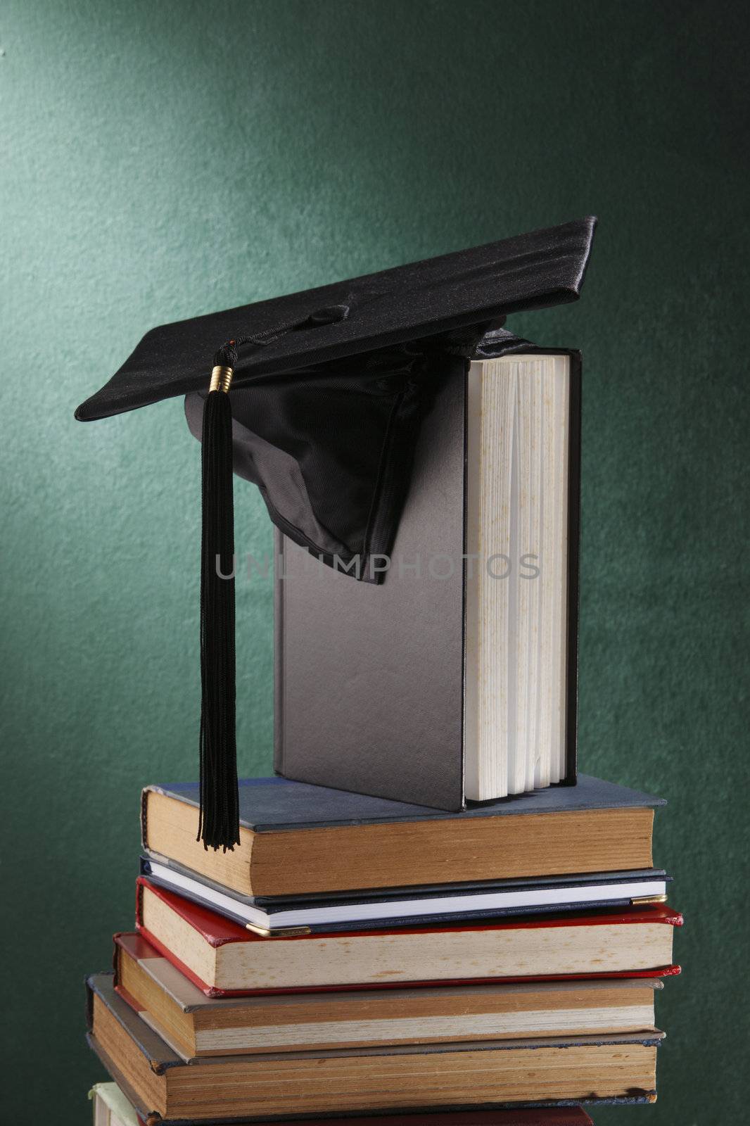 Graduation cap with book  in front of black board