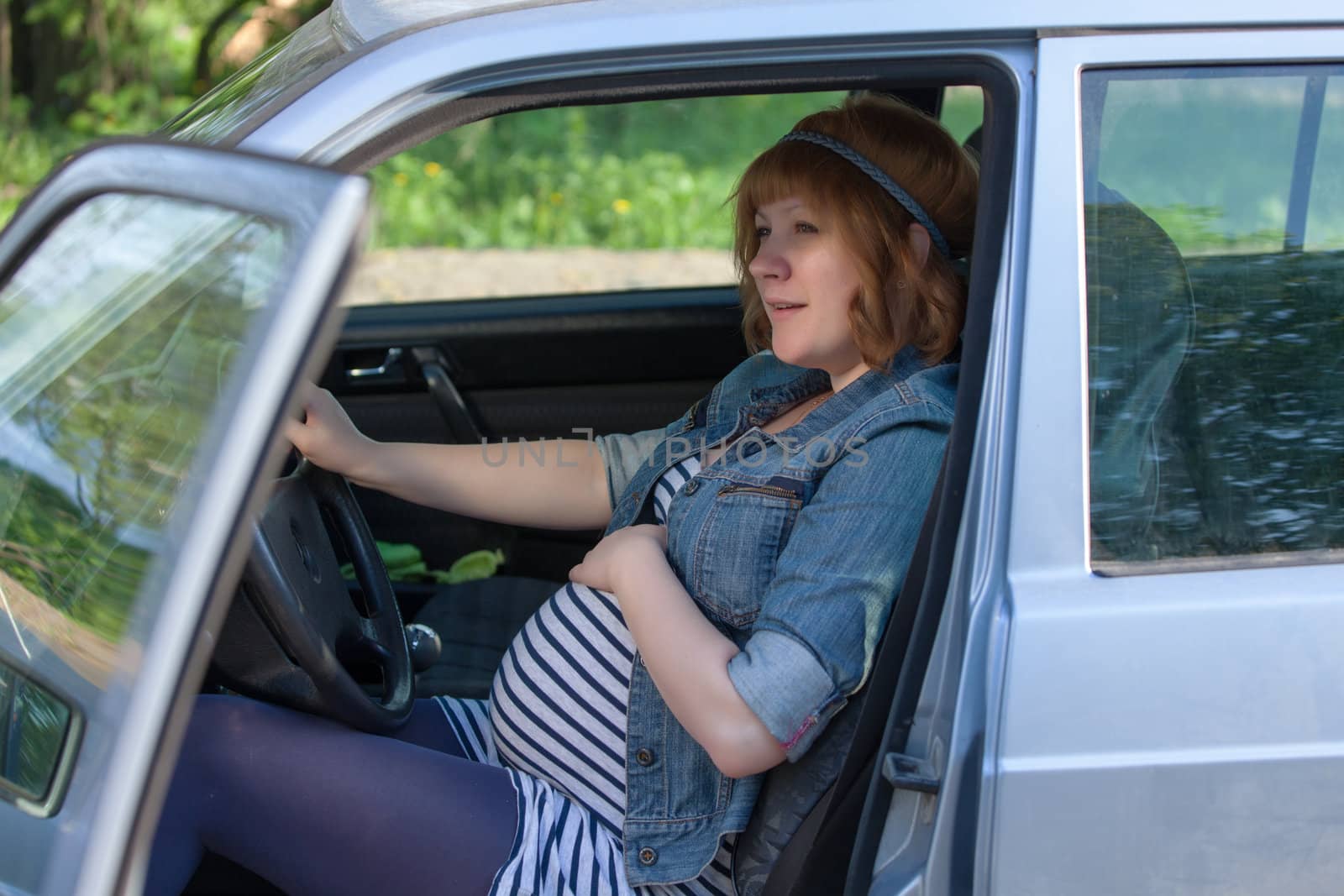 Pregnant woman speaking to her belly in the car by Discovod