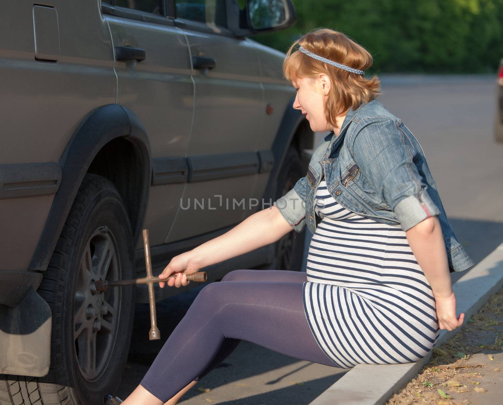 Pregnant Woman with a Wheel Brace near Car