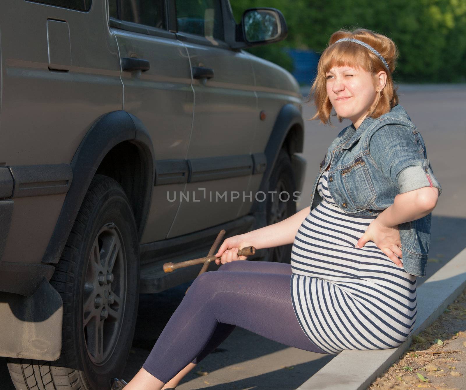 Pregnant Woman with a Wheel Brace near Car by Discovod