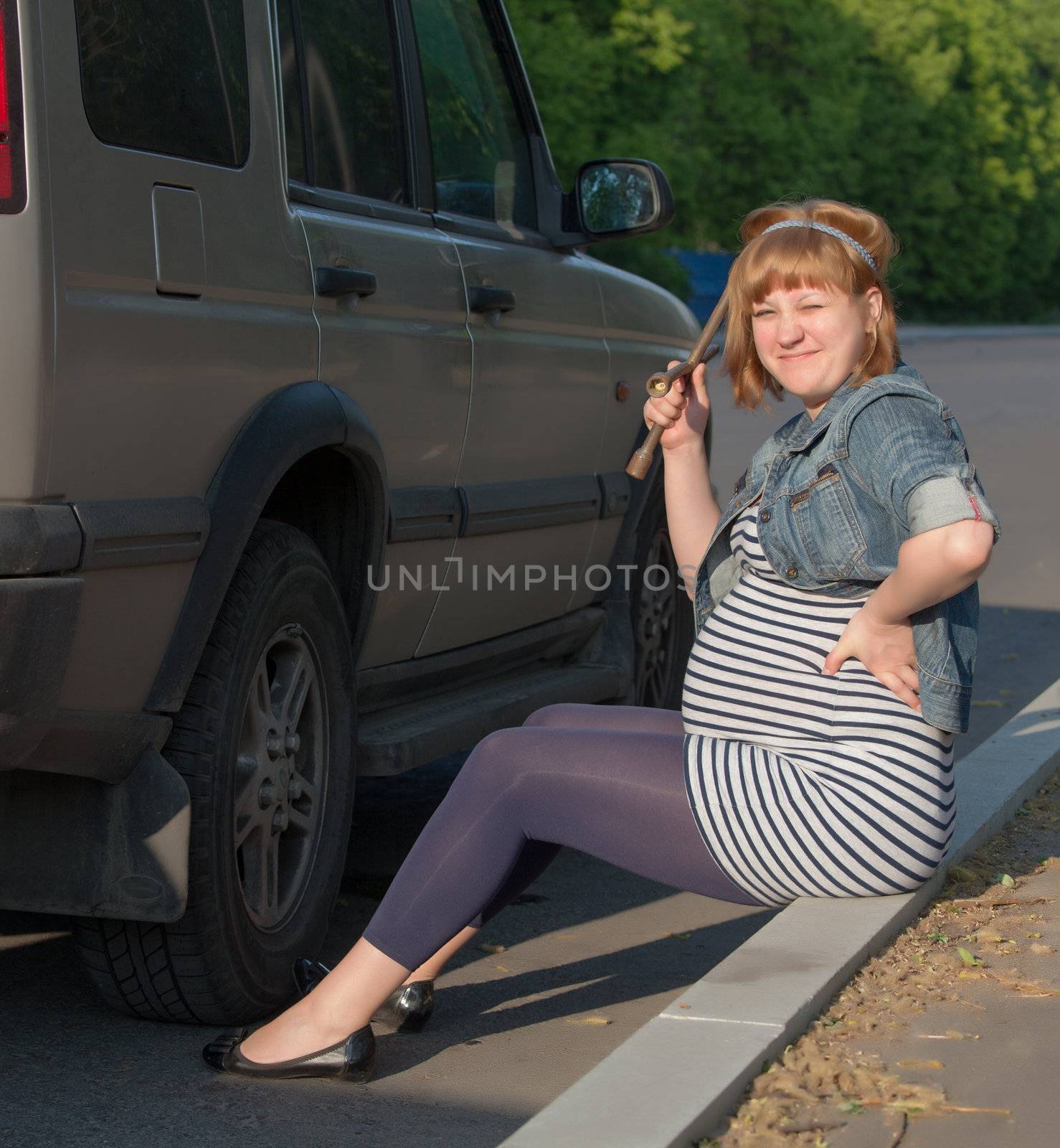 Pregnant Woman with a Wheel Brace near Car