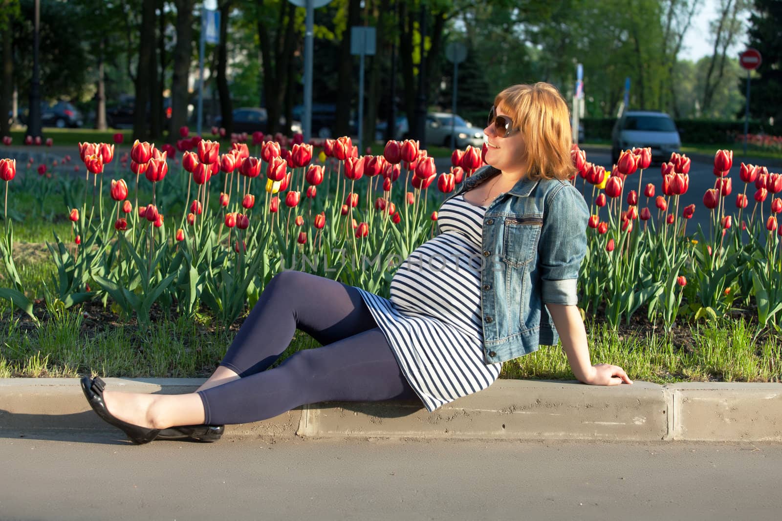 Pregnant woman sitting near tulip flowerbed