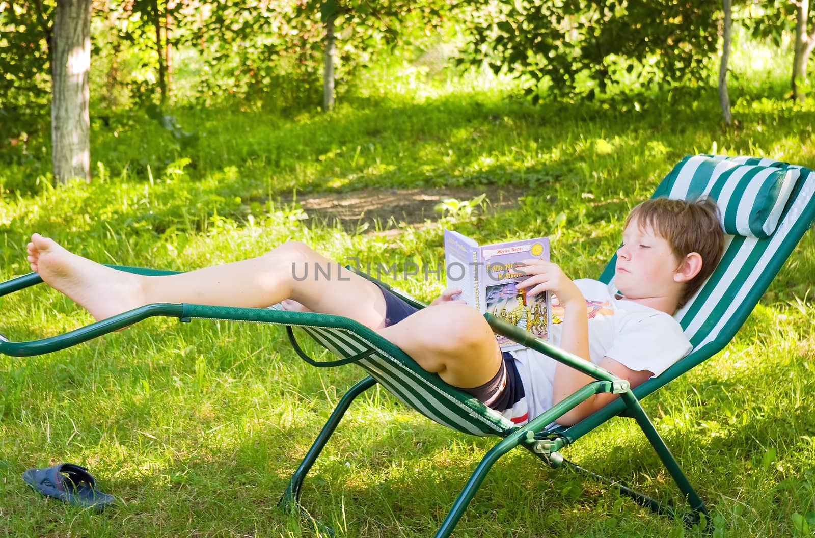 Boy in silence in the garden reading a book 