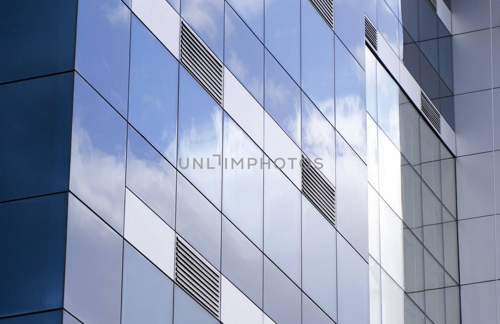 The ventilation grids, exterior facade of a building covered with glass reflections of the clouds taken. ventilation grills to be emphasized in this photograph and the glass-clad building on the original.