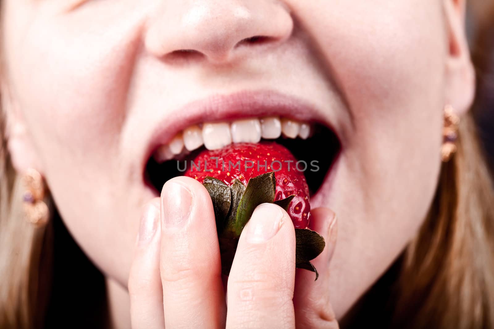 Young woman eating fresh juicy strawberry