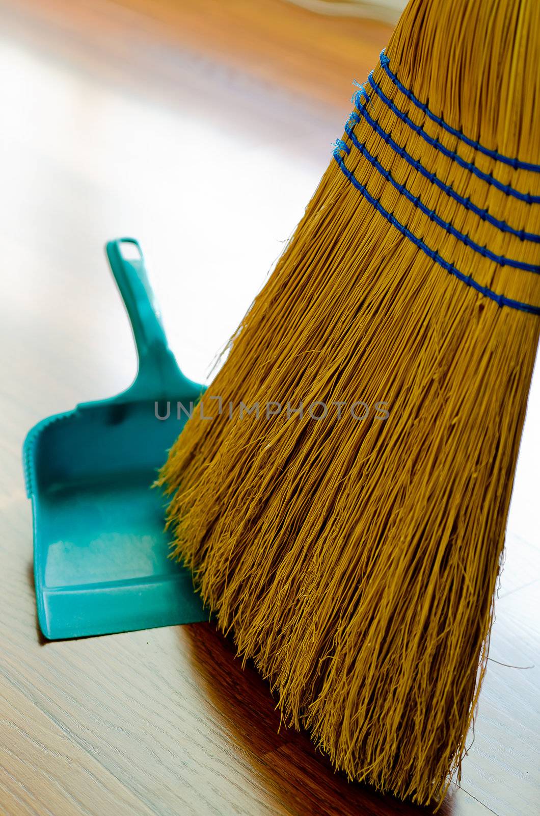 Broom and dust pan on hardwood floor.