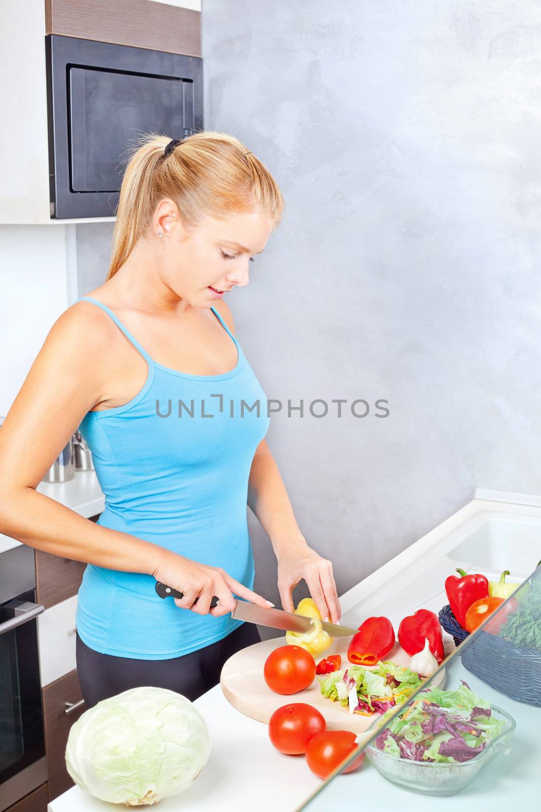 Young woman in kitchen cutting vegetables by imarin