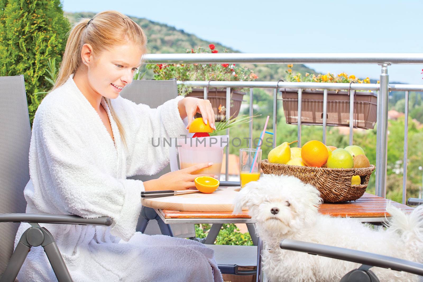 Woman making morning juice on terrace with her dog