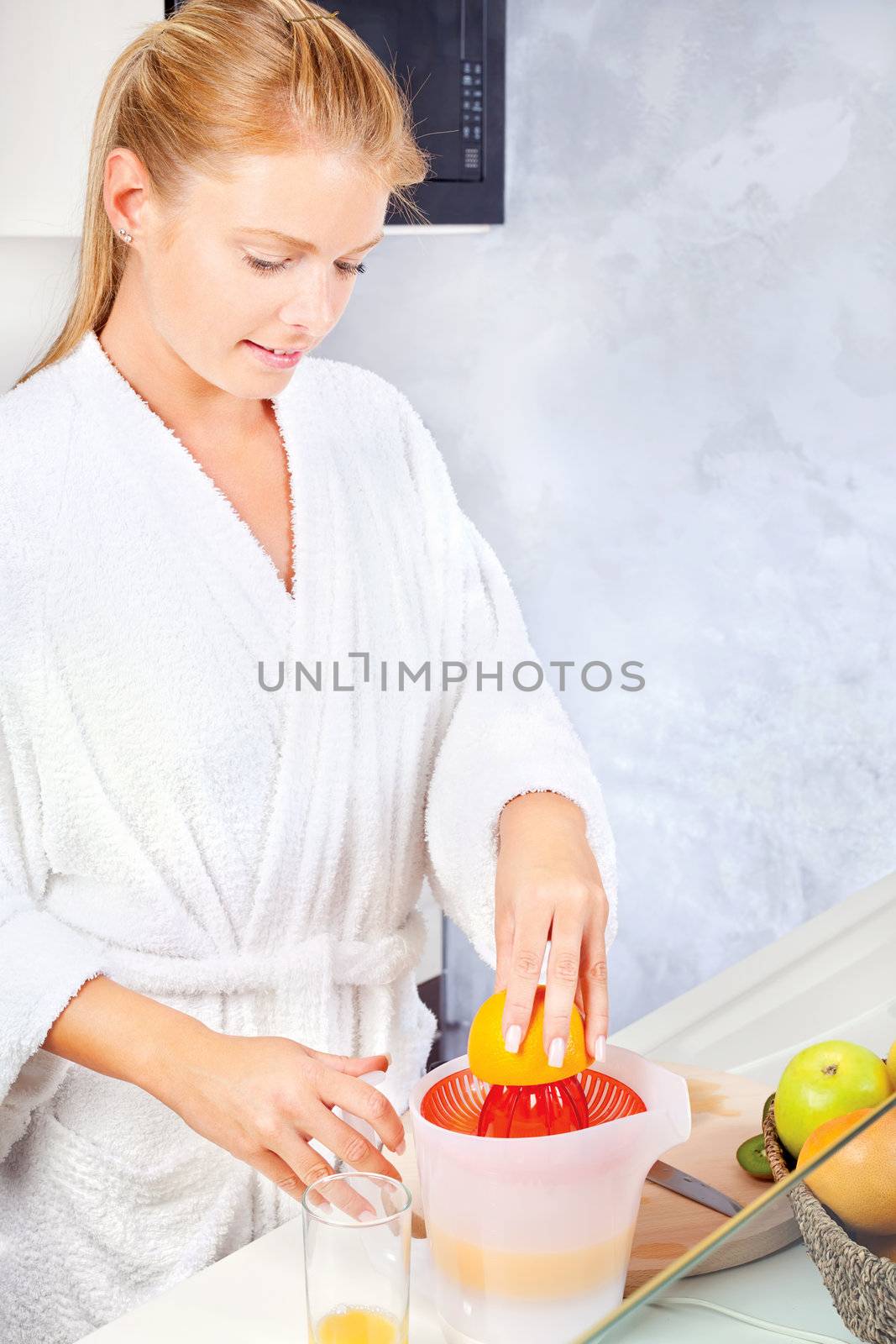young woman making morning juice in kitchen