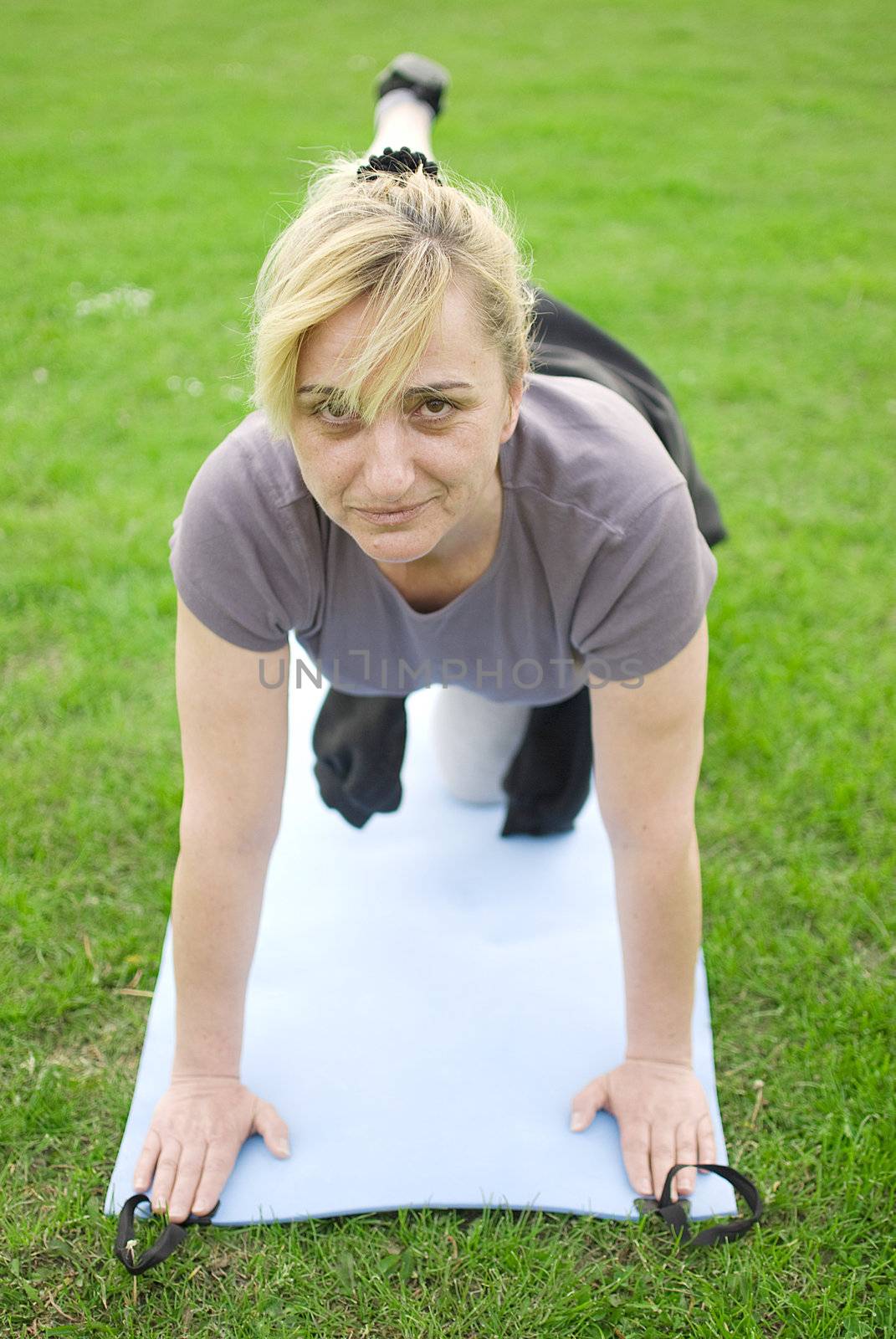 middle aged woman keeping fit with exercises in a park