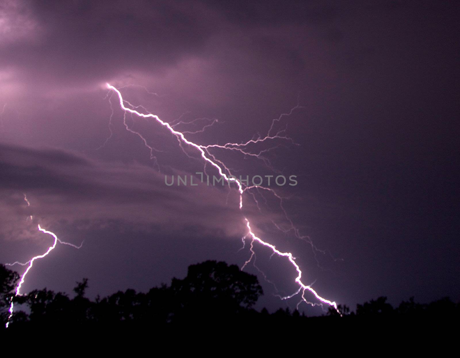 Bolts of lightning cross the purple night sky