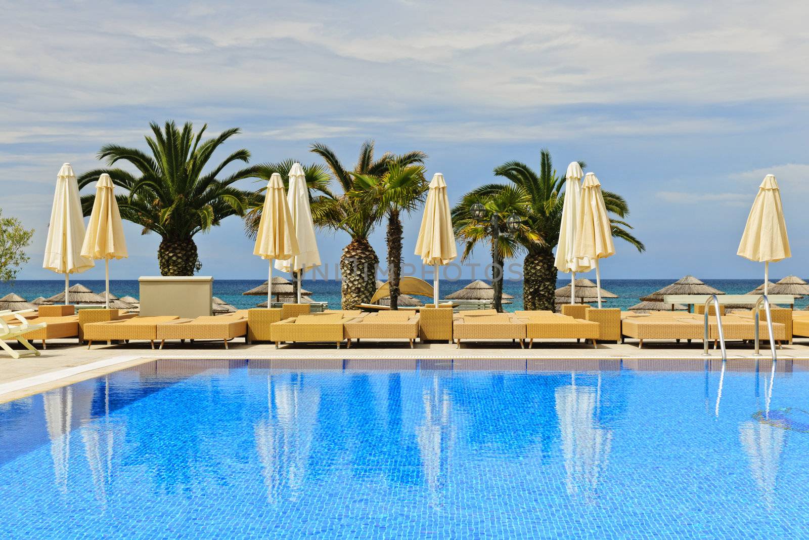 Idyllic swimming pool at tropical resort with palm trees in Greece
