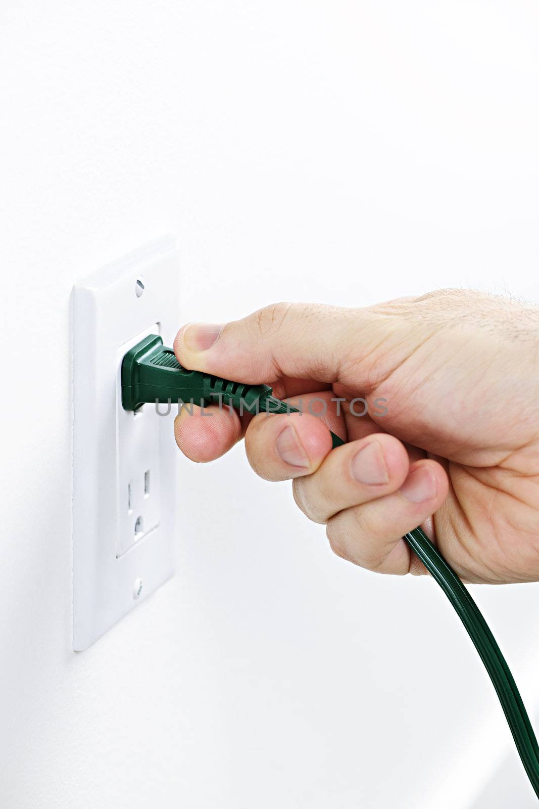 Hand pulling green electrical plug from outlet