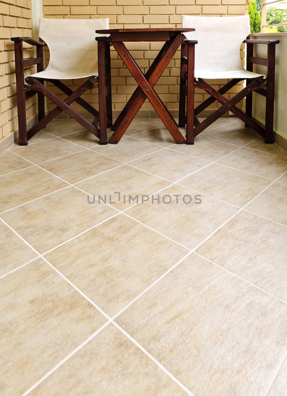Wooden chairs and table on ceramic tile floor of balcony