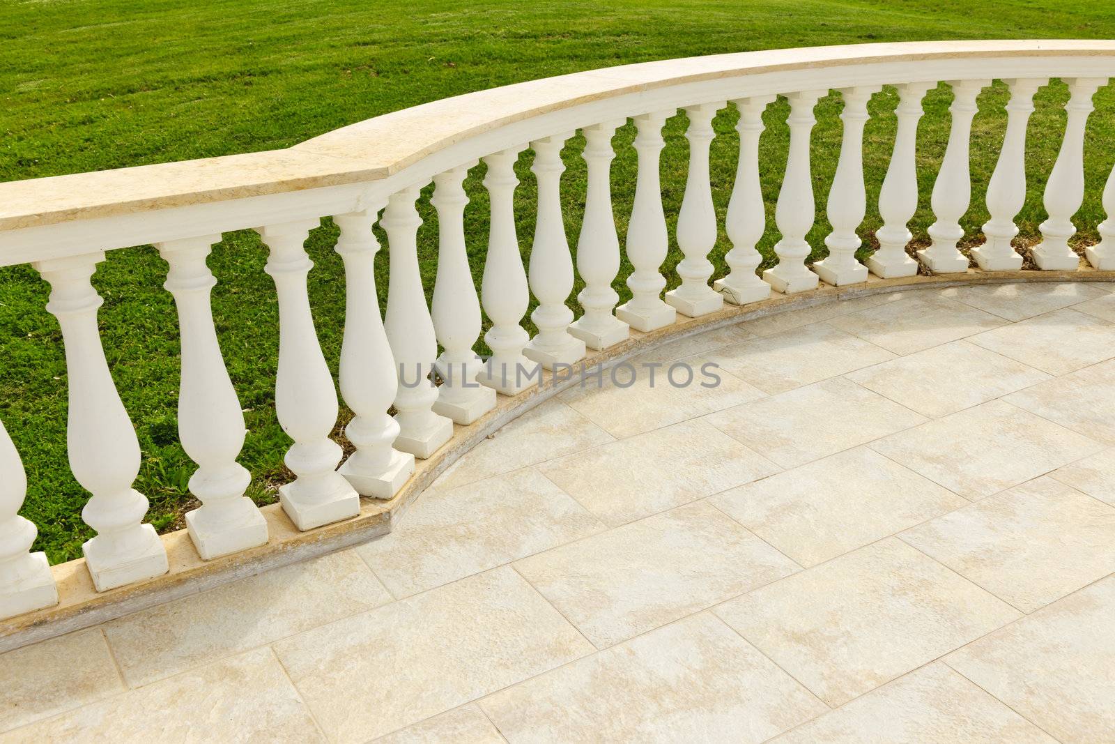 Fancy marble railing on ceramic tile patio with lawn