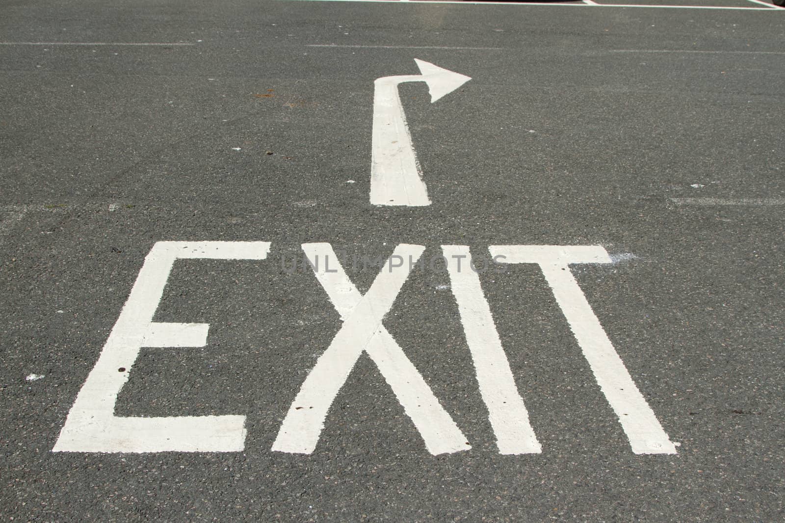 A tarmac road with the word, 'EXIT' and a directional arrow painted in white.