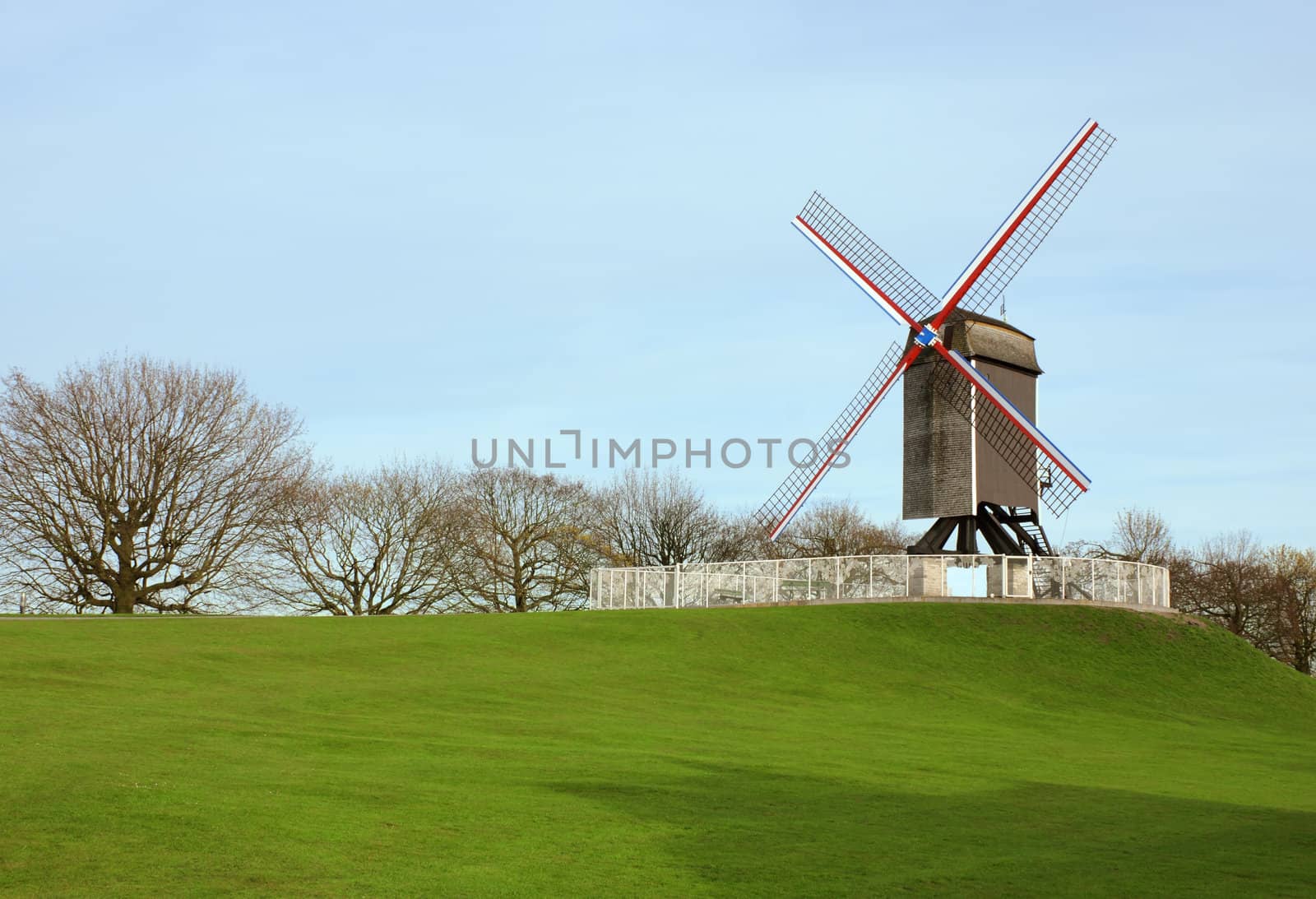 Windmill in Bruges, Belgium shot of green grass and blue sky background.