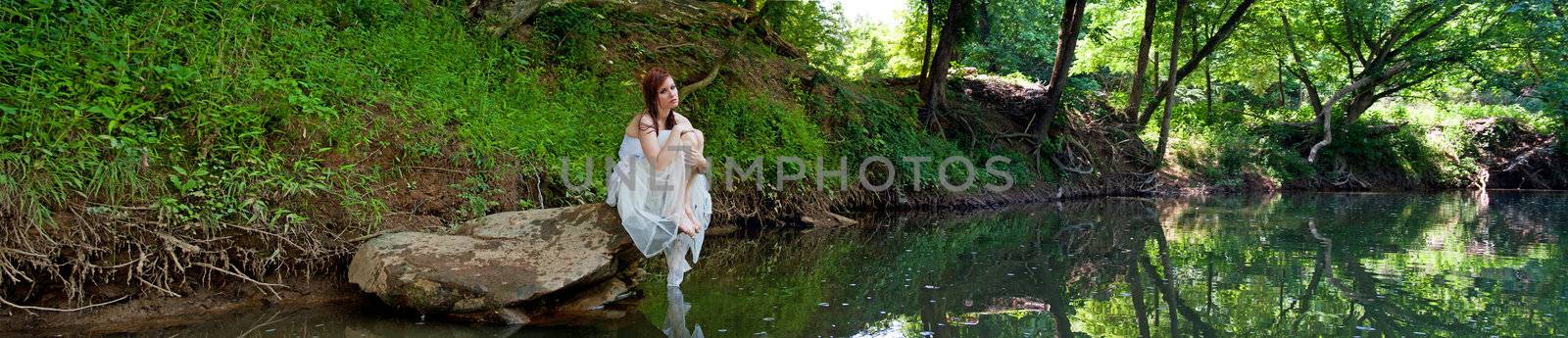 A sad bride sitting on a rock, panorama