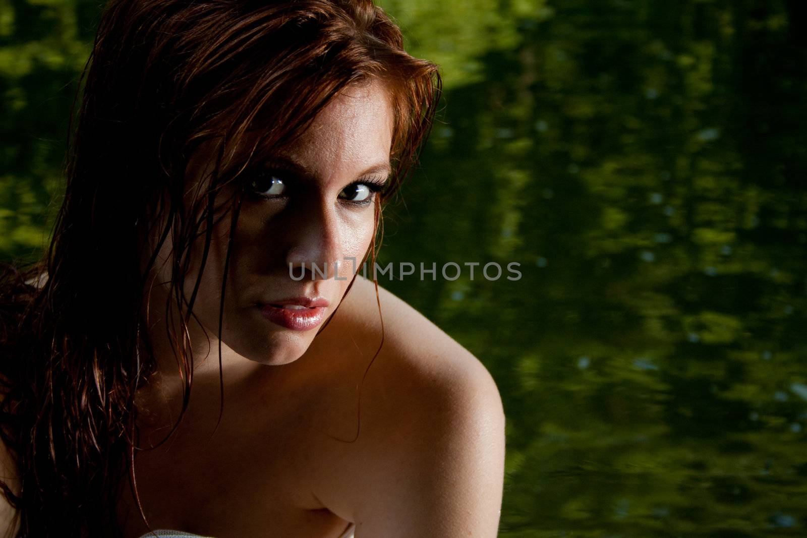 A closeup of a beautiful woman, in front of green water