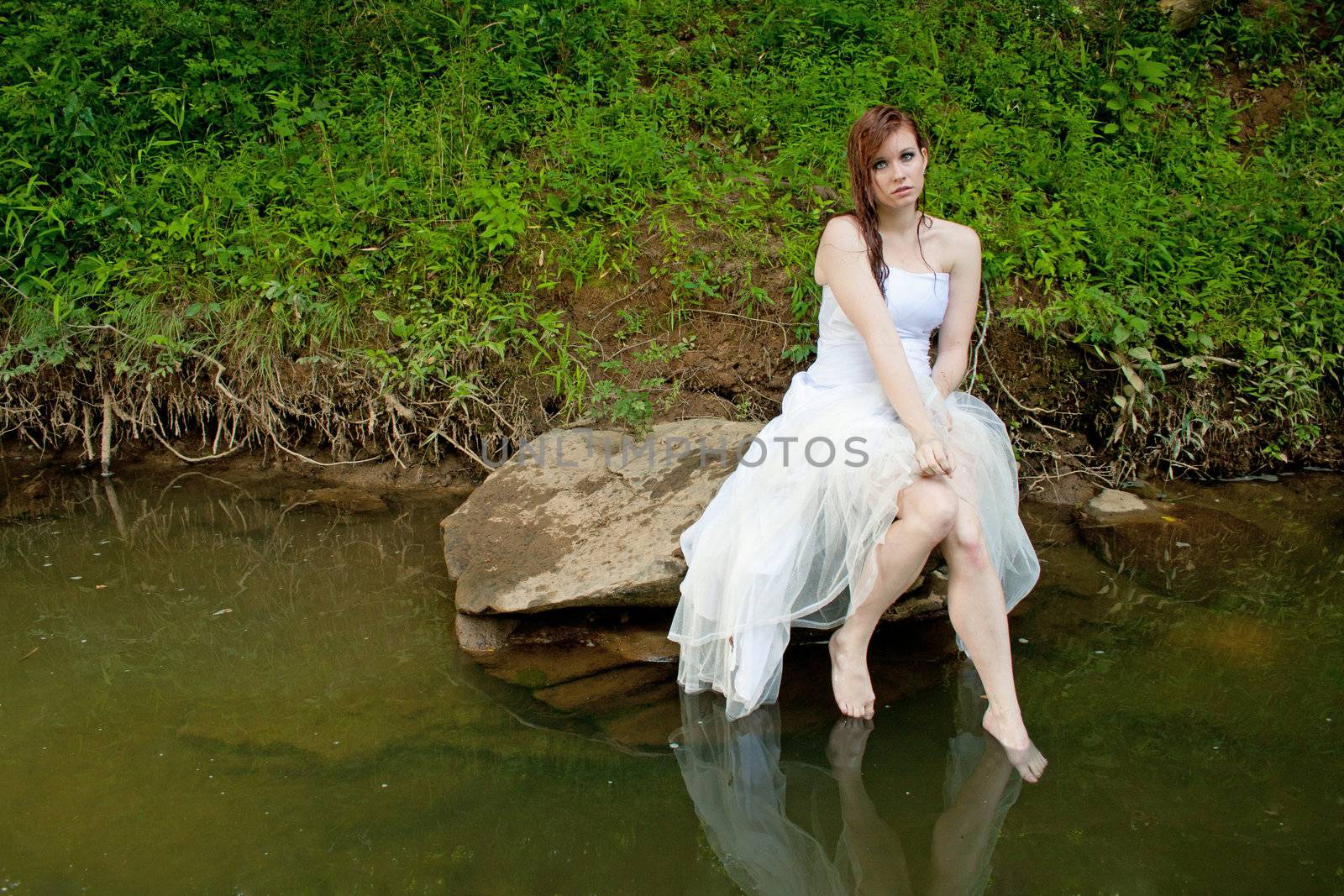 Wet woman sitting on a rock over the water by mahnken