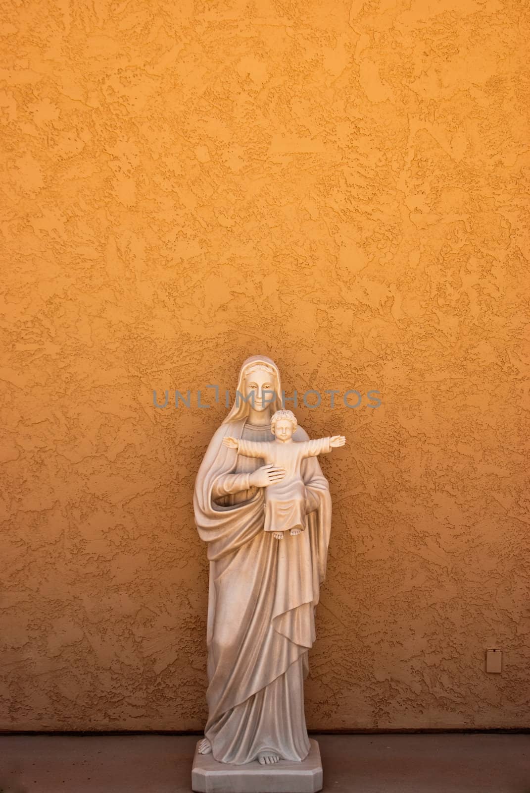 Statue of mother and child on orange adobe wall