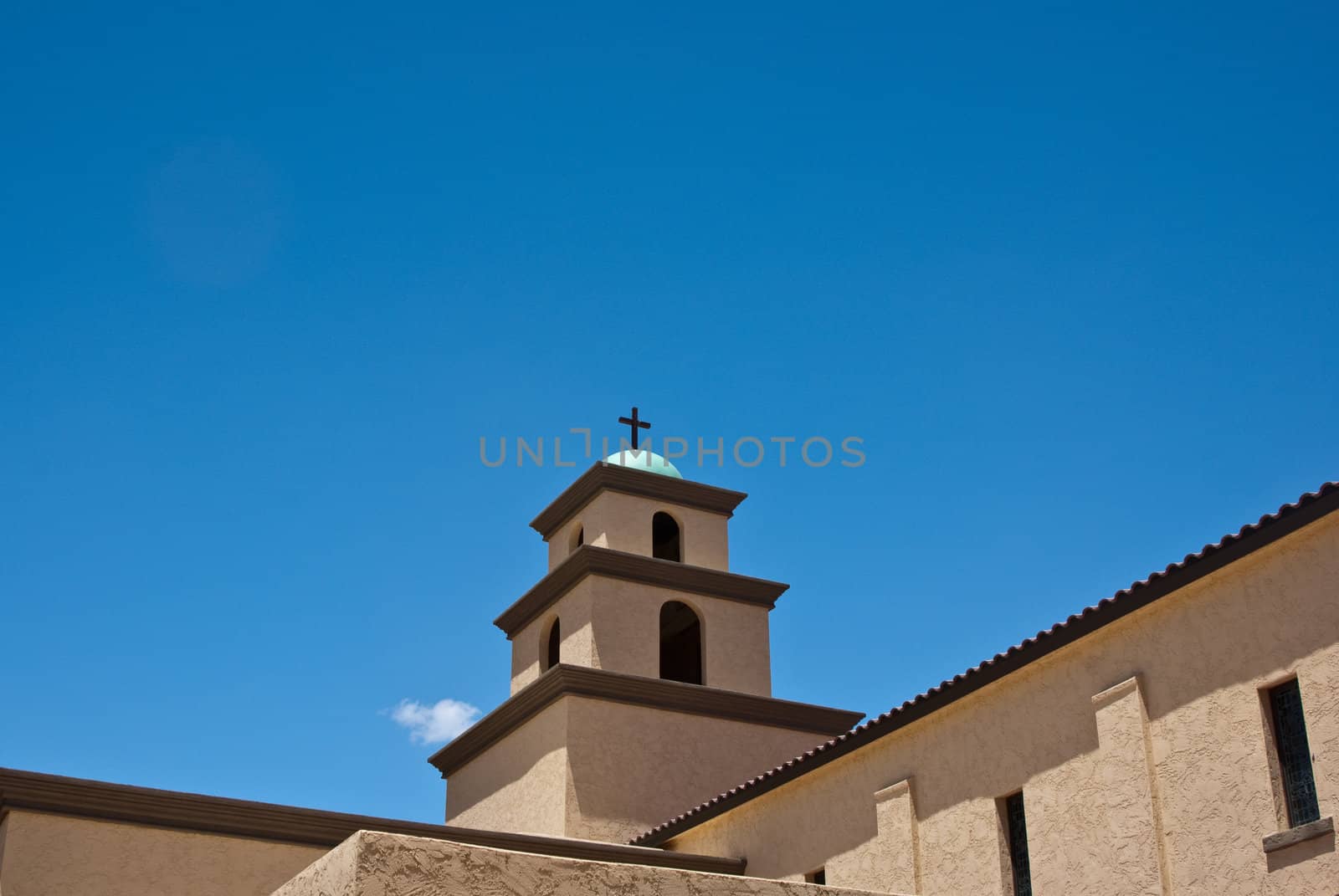 Desert church rooftop with dome and cross on blue sky