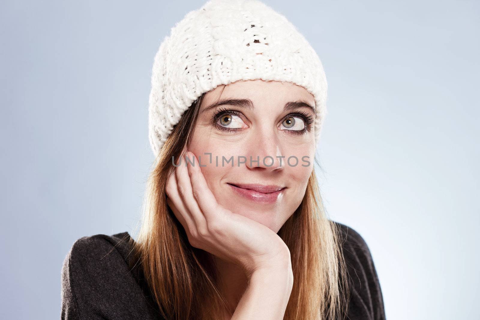 woman with a winter cap looking up on light blue background