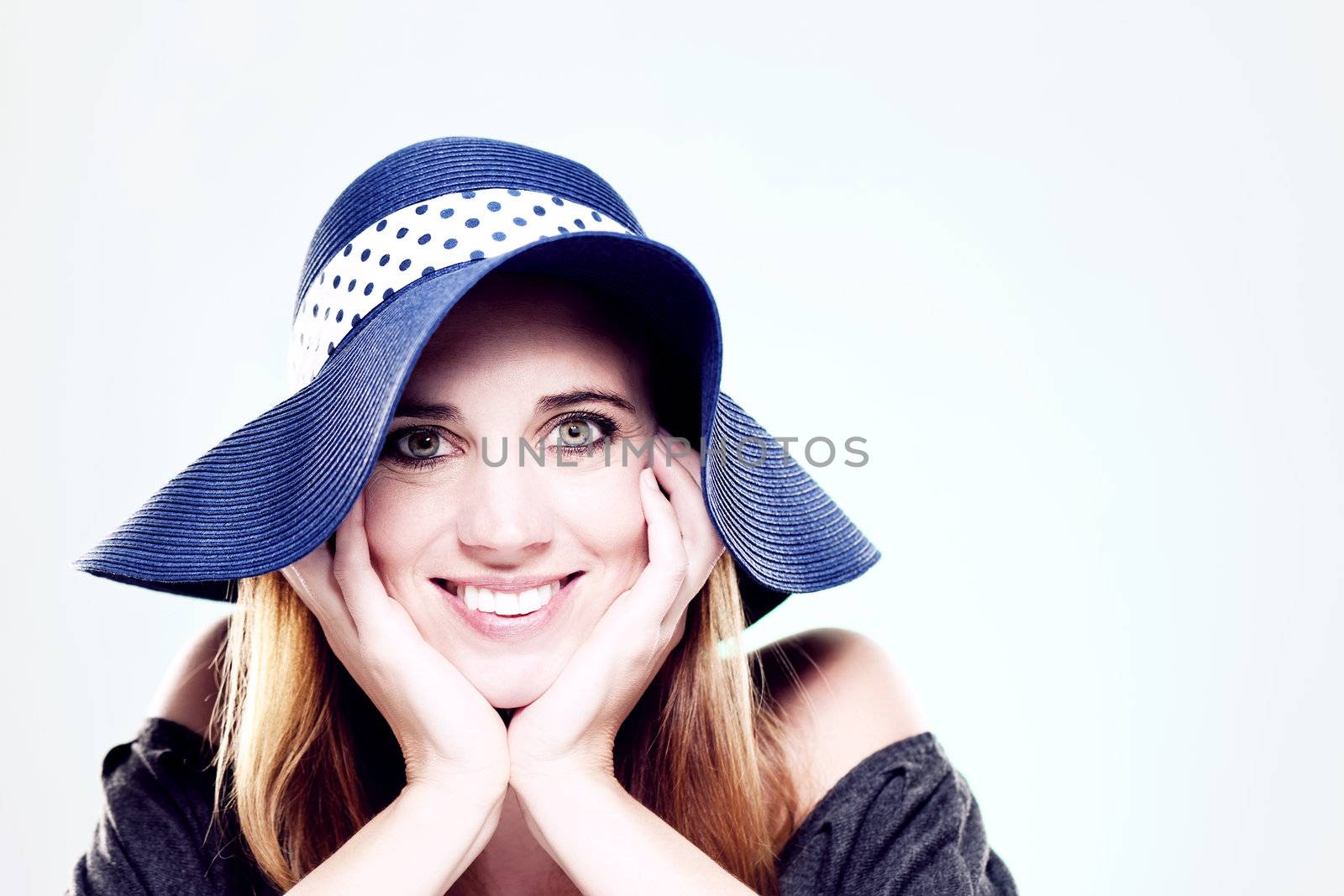 happy woman wearing a summer hat on light blue background