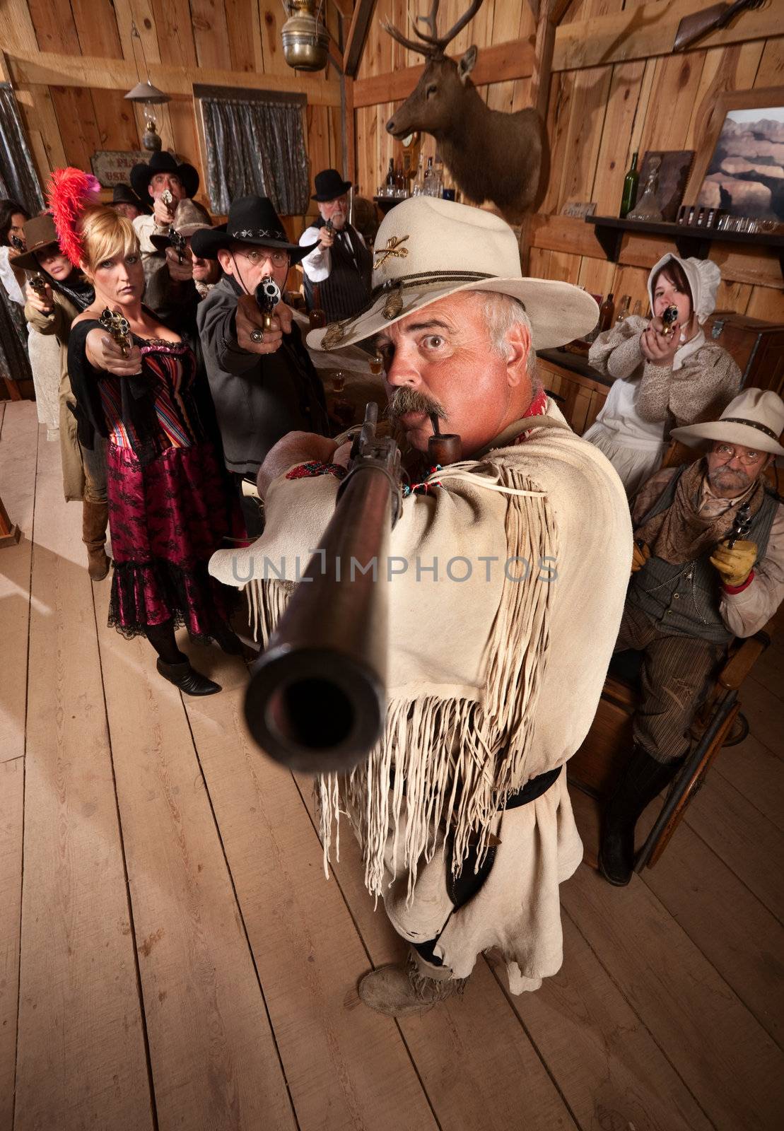 Old west cowboy and group point their weapons in a saloon
