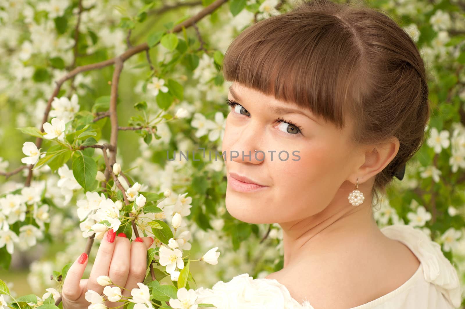 beautiful young brunette woman with the apple tree on a warm summer day