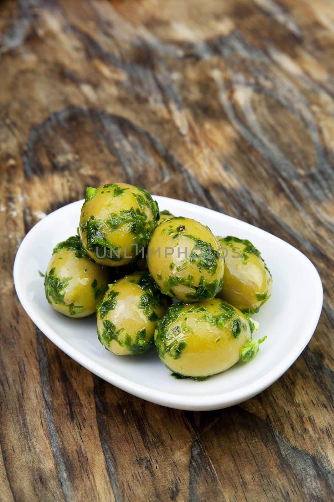 green olives with fresh bread and herbs on wooden background