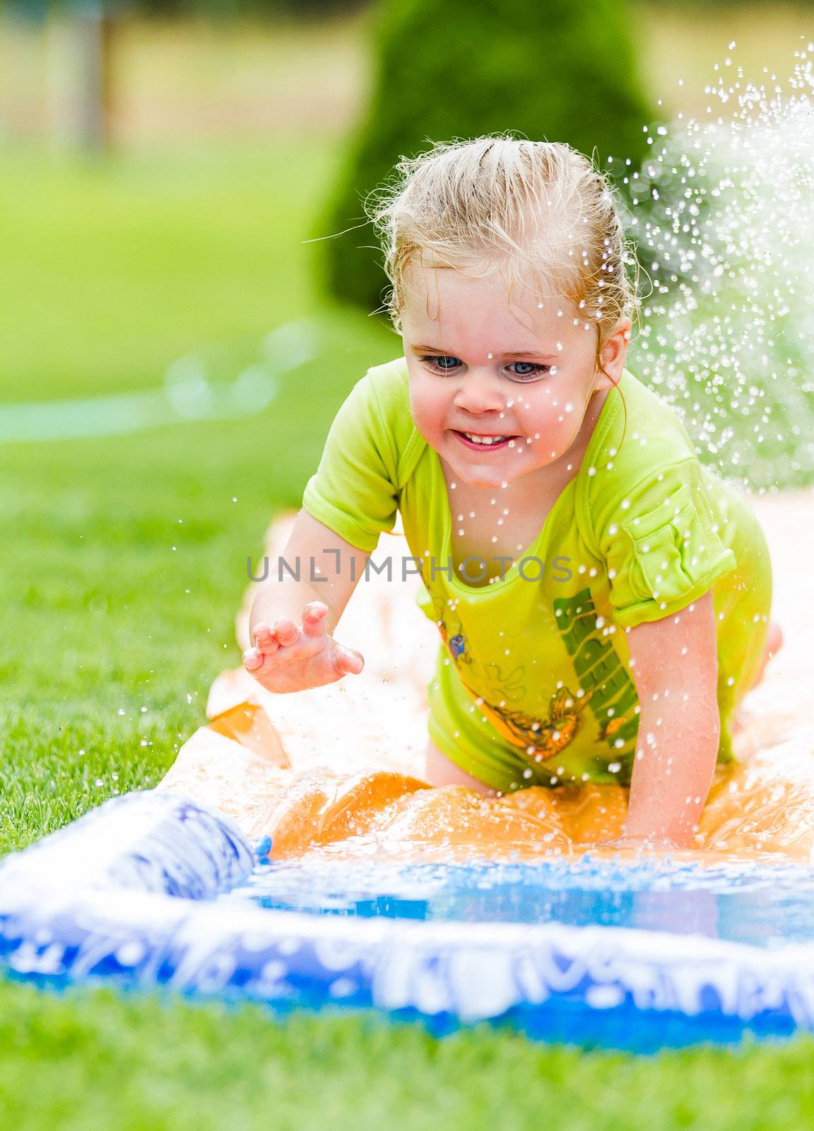 Young happy girl sliding down a water slide