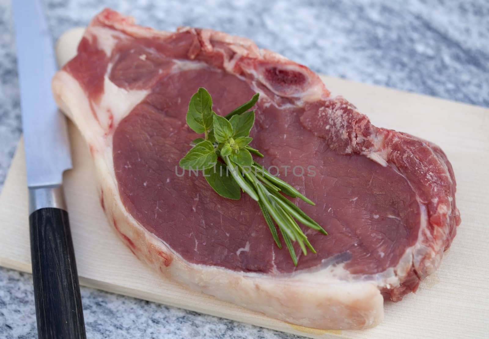 Raw Beef steak decorated with rosemary and oregano