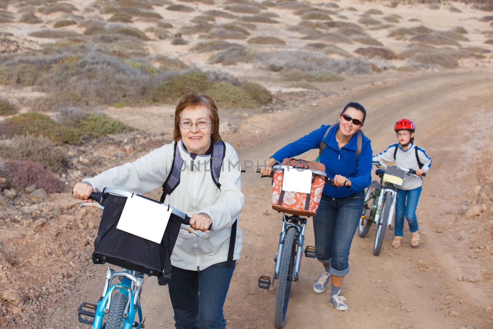 Girl with her mother and grandmother having a weekend excursion on their bikes on a summer day in beautiful landscape
