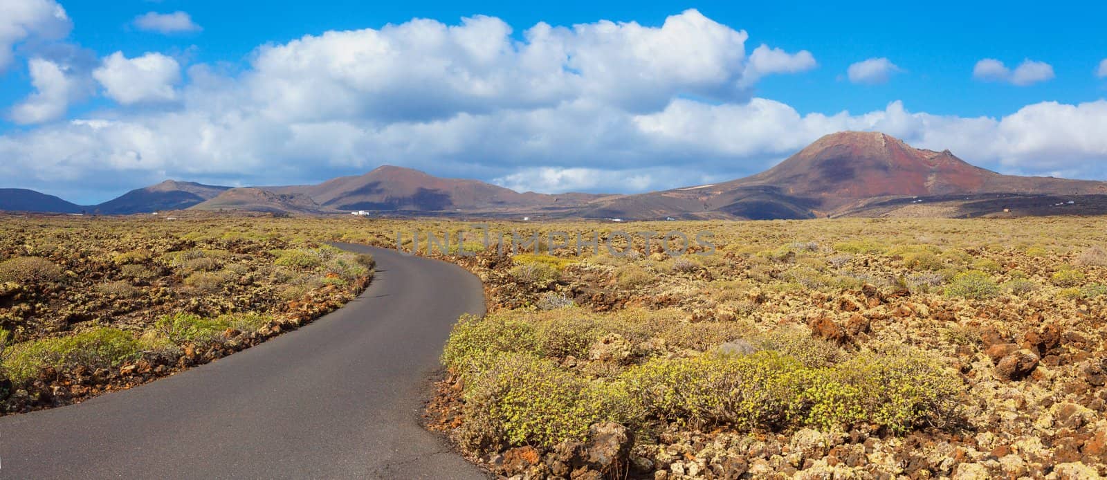 Panorama of empty road crossing the lava in the mountain, Lanzarote, Canary islands, Spain. Vertical view