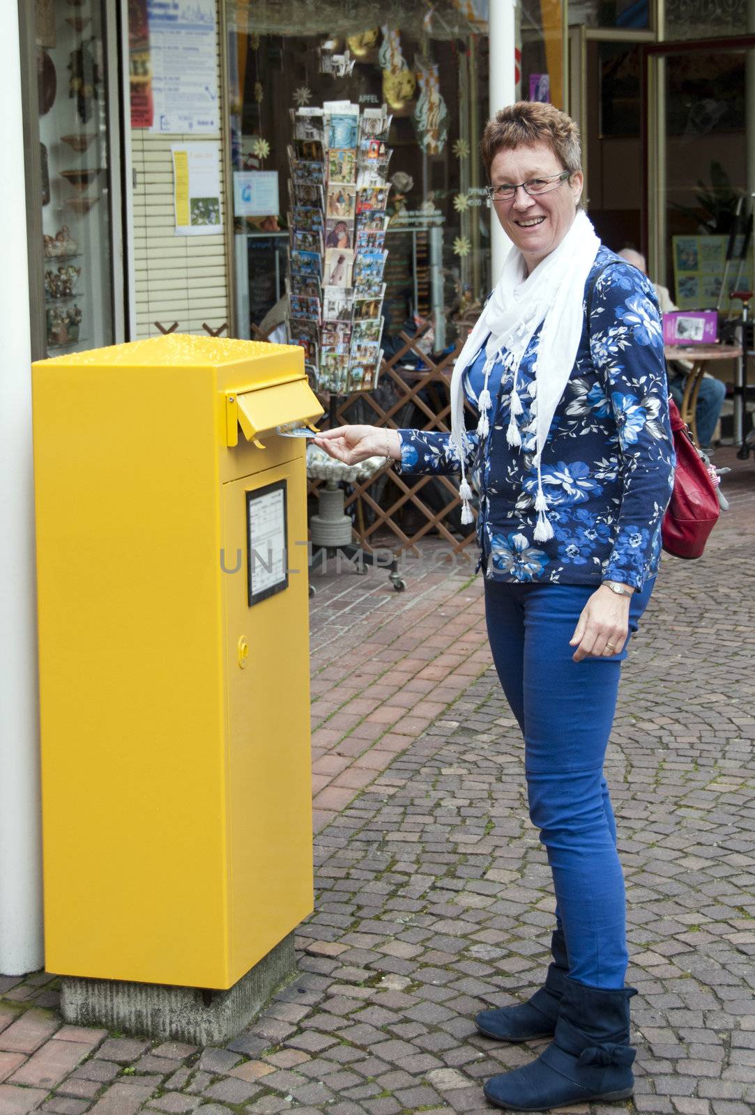 woman posting a post card in a mailbox