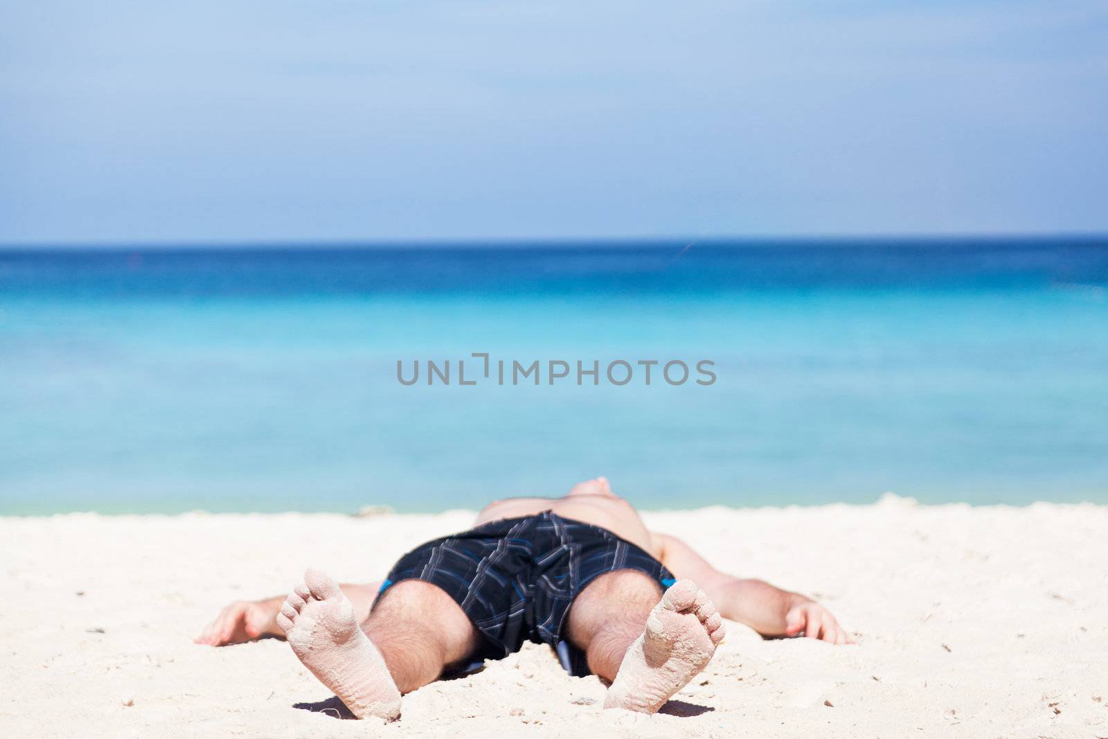 Man lies on a beach on an ocean coast