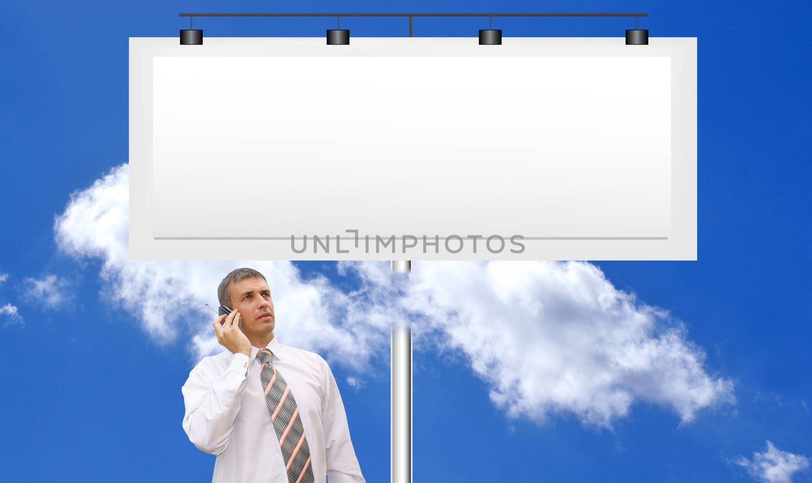 The successful businessman against a publicity board and the bright blue cloudy sky