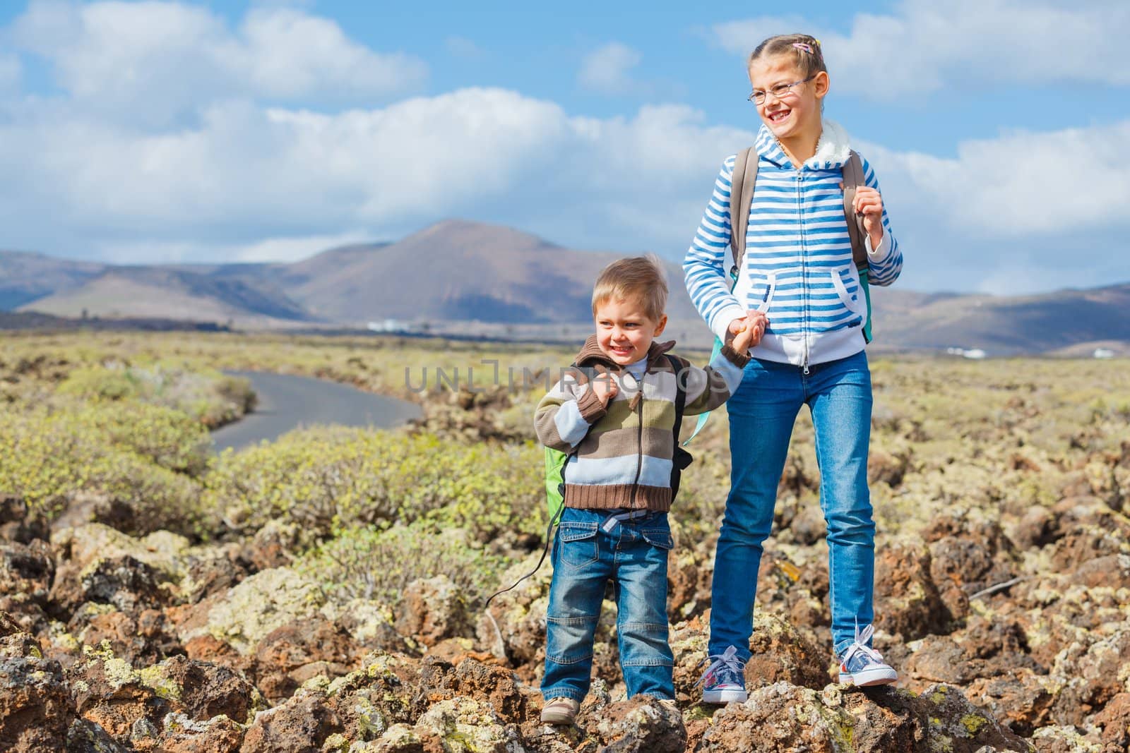 Cute little boy and his sister with backpack have trip in the mountains