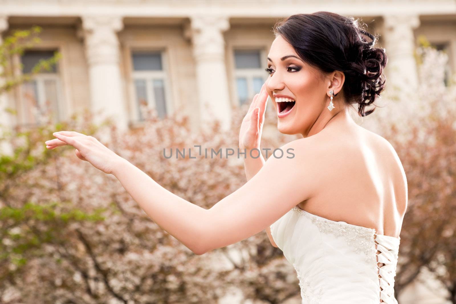 Happy beautiful bride dancing in wedding dress outside