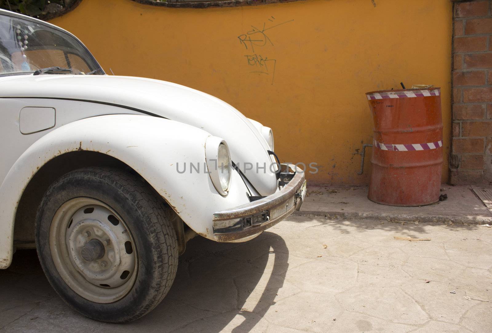 An old white car parked on the side of the road in mexico.