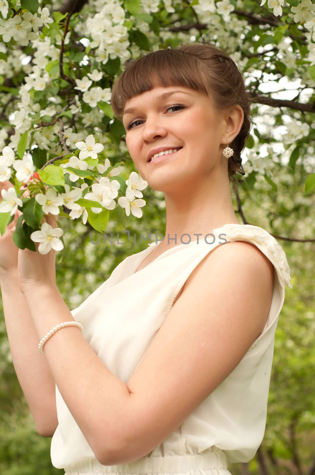 beautiful young brunette woman with the apple tree on a warm summer day