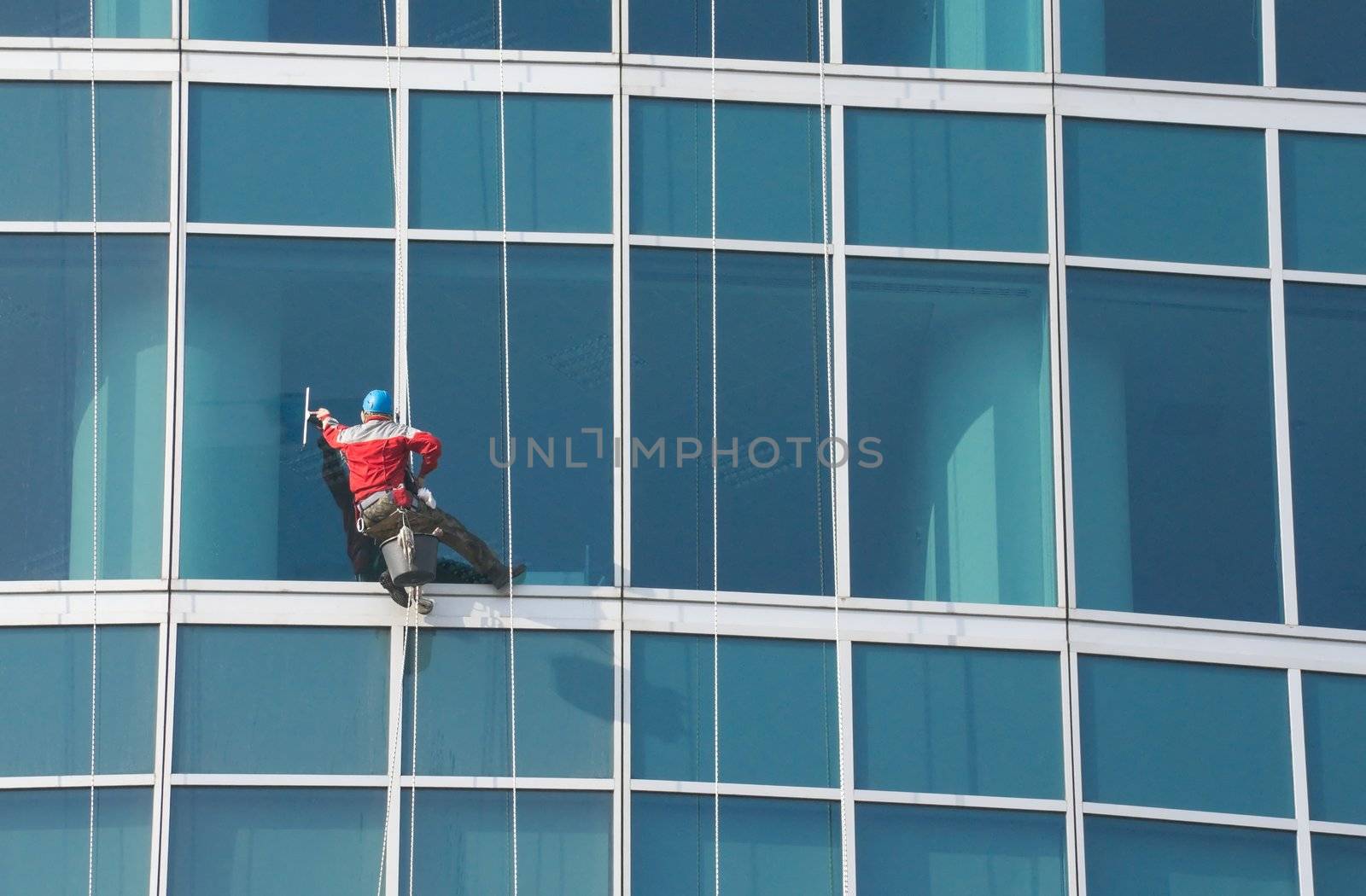 Climber - window cleaner perform the work at wall of an office building