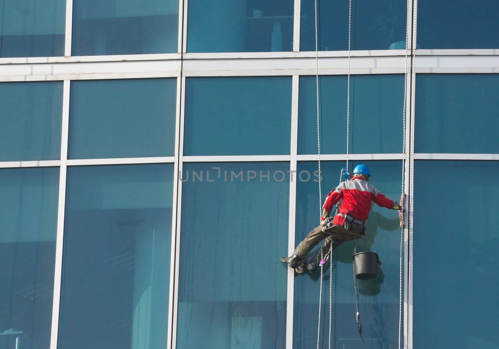 Climber - window cleaner perform the work at wall of an office building