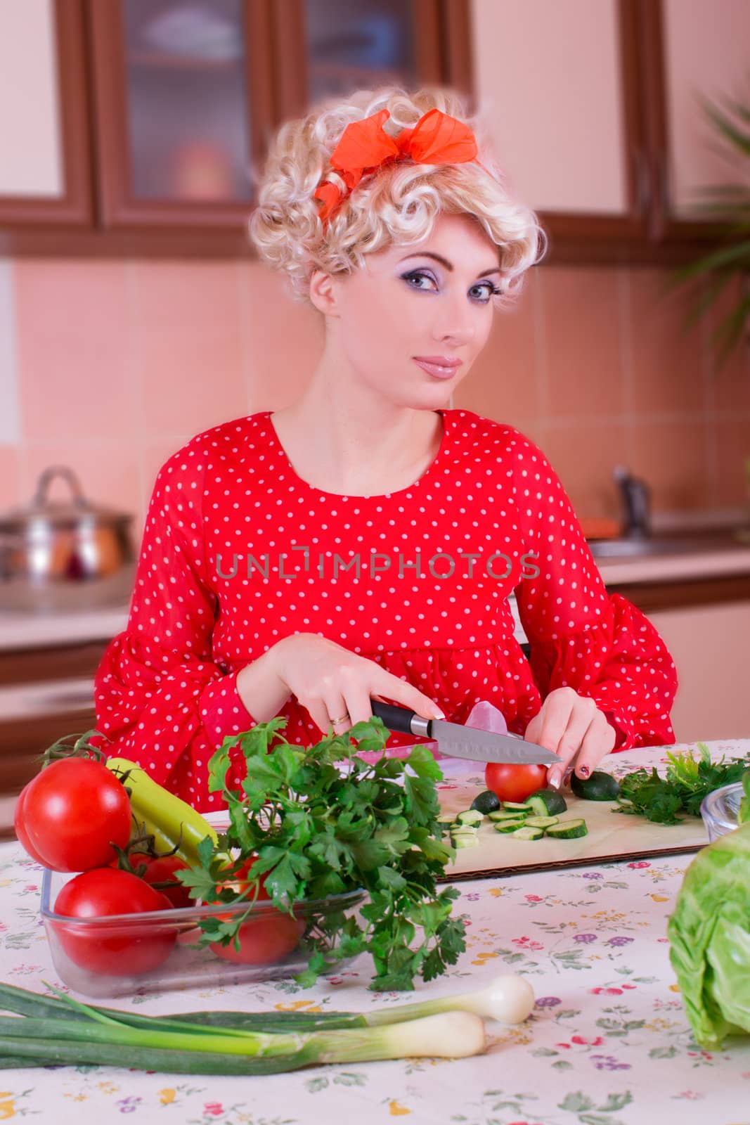 Pinup woman in red cutting vegetables in kitchen