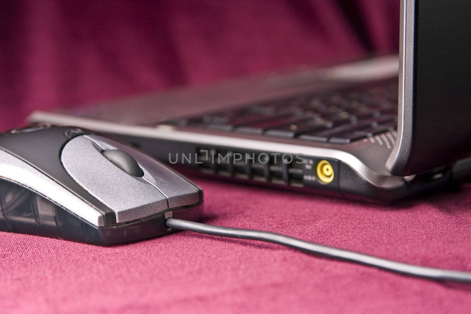 The grey computer mouse and modern laptop on a claret background